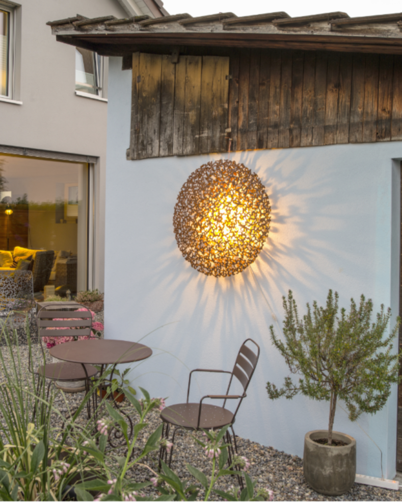 Sole Leuchte hängt an Wand im Garten