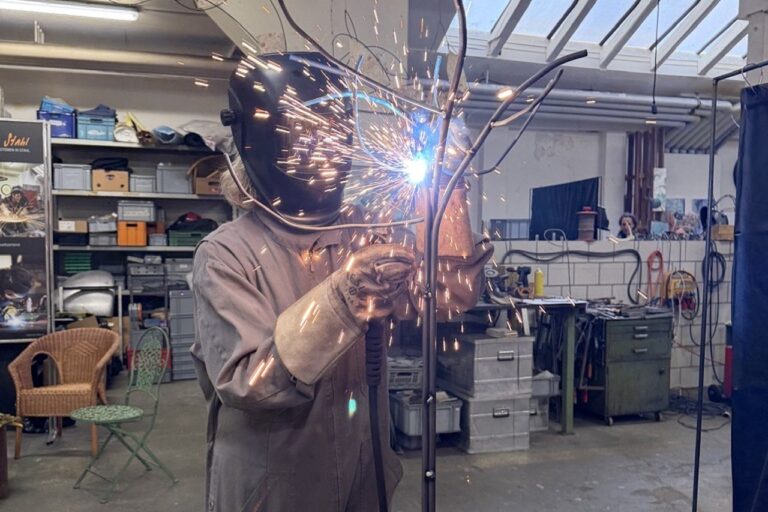 Frau schweisst an einem Metallbaum